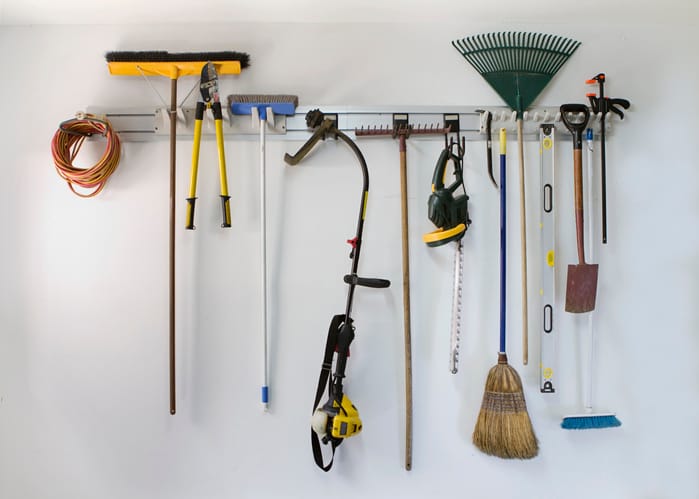 Yard tools hanging from hooks on the garage wall