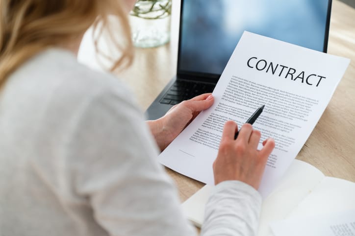 A woman looking at a paper document titled CONTRACT.